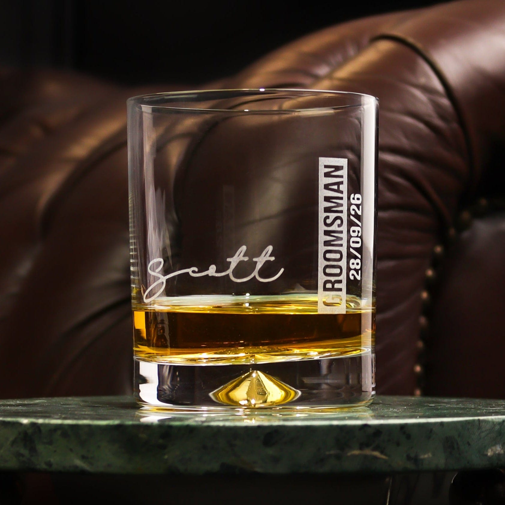 a glass tumbler on a table that is engraved with the recipients name,role and date of the wedding, a great groomsman gift idea for your wedding by handford and mason