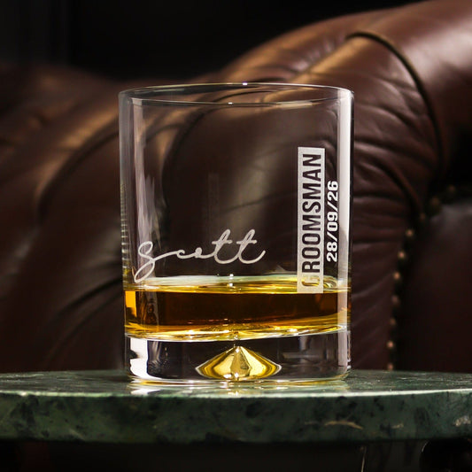 a glass tumbler on a table that is engraved with the recipients name,role and date of the wedding, a great groomsman gift idea for your wedding by handford and mason