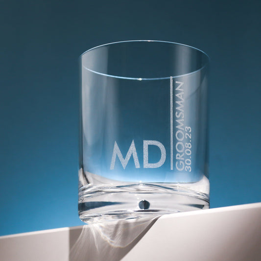 a glass tumbler on a table that is engraved with the recipients name,role and date of the wedding, a great groomsman gift idea for your wedding by handford and mason