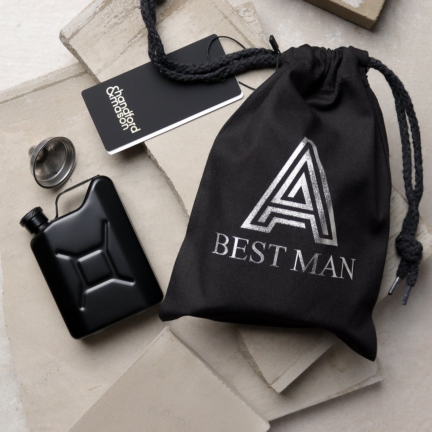 a picture of an hip flask which is a miniture jerry can in a matte black finish,there is also a black bag that it goes in whichis personalised with the recipients initial and role at the wedding, creating the perfect wedding groomsman gift.